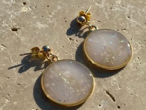 Boucles d’oreilles rondes marbrées holographiques et dorées.